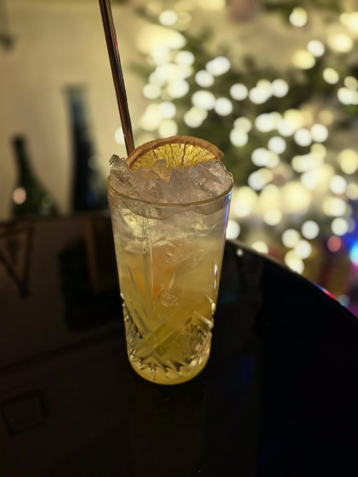 Cocktail de création servi dans un verre taillé sur un comptoir en bois