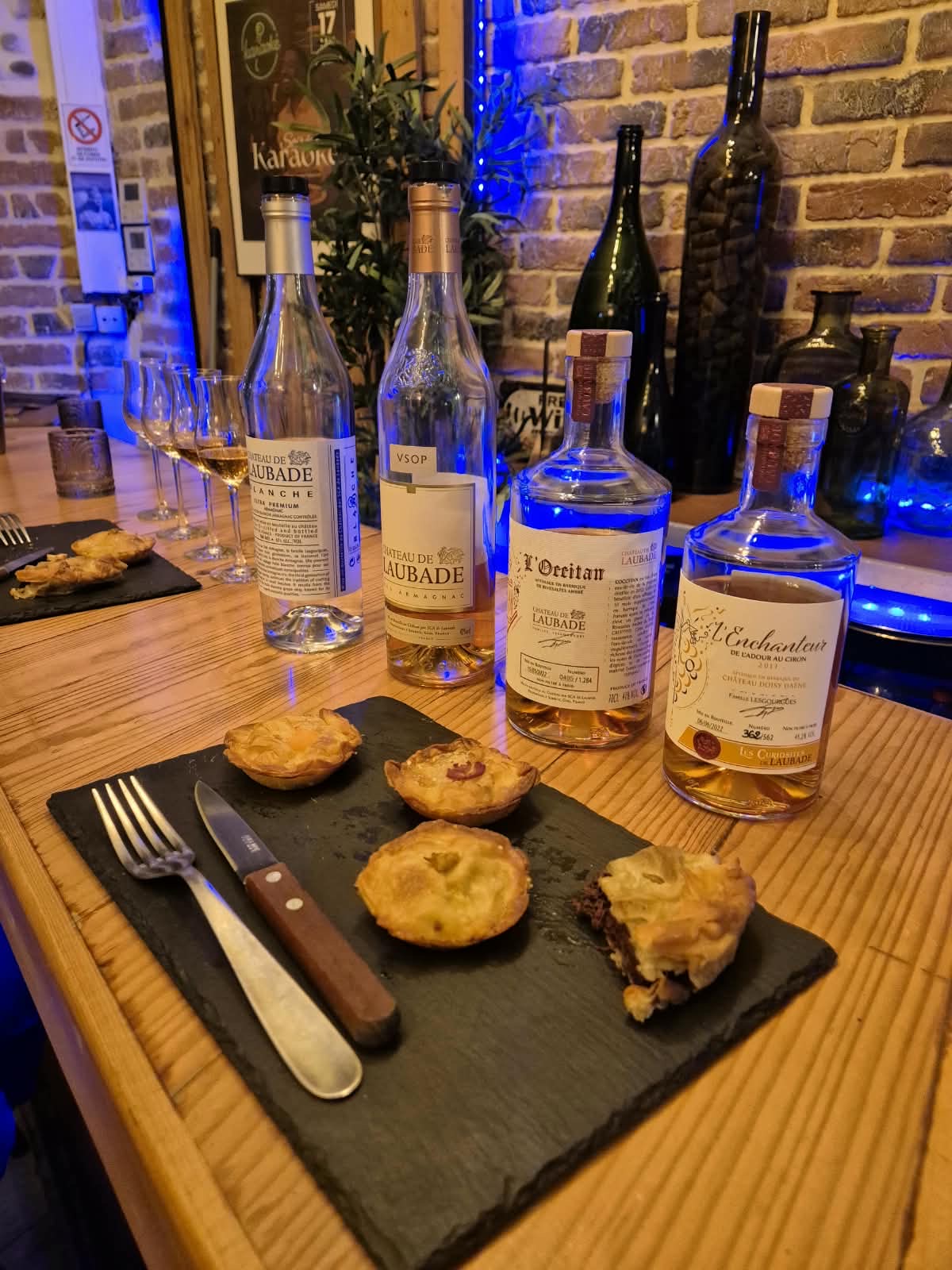 Bouteilles d'Armagnac et accompagnements à partager sur une table en bois d'Œno Bar
