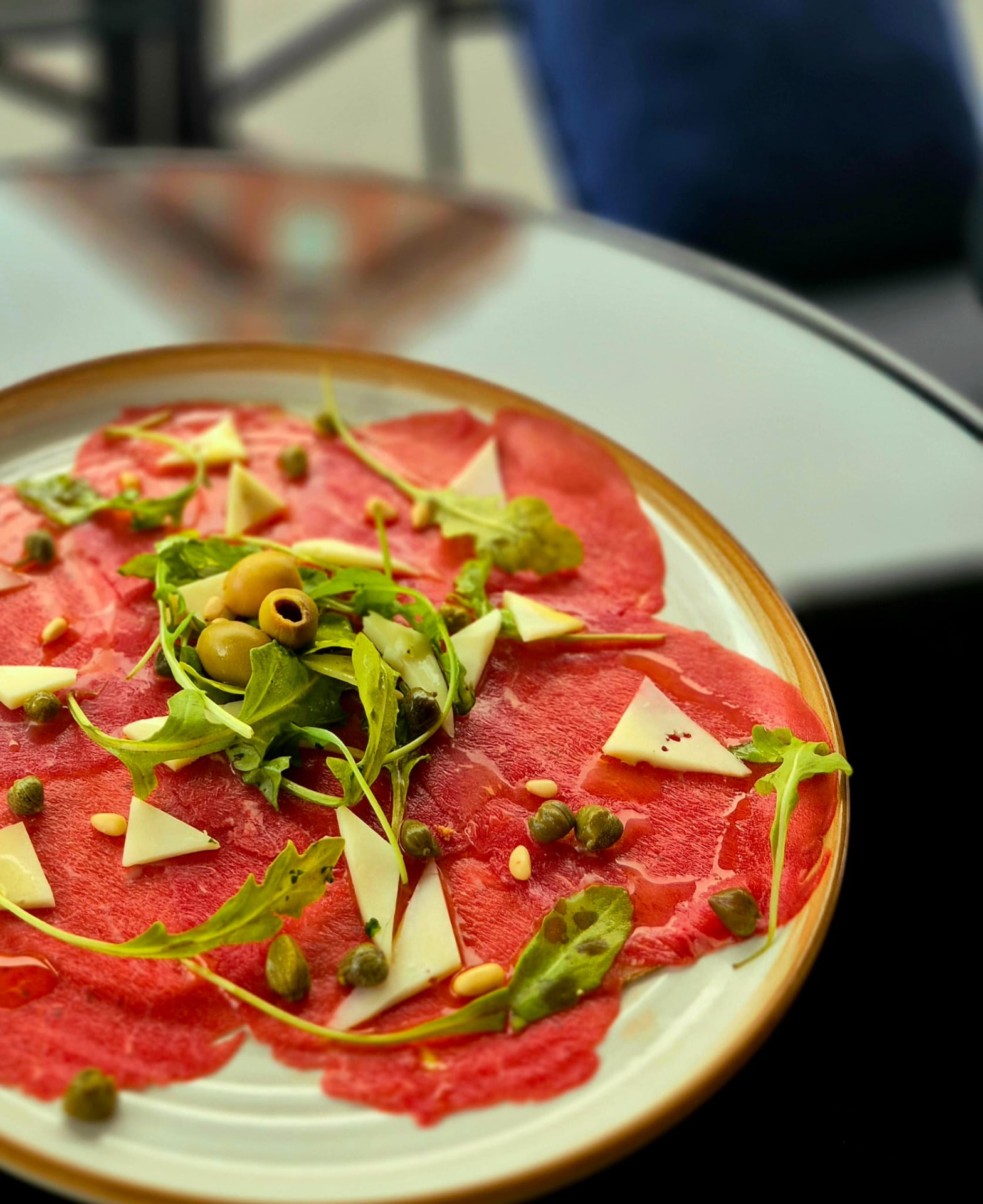 Assiette de carpaccio garnie de roquette, olives et copeaux de parmesan
